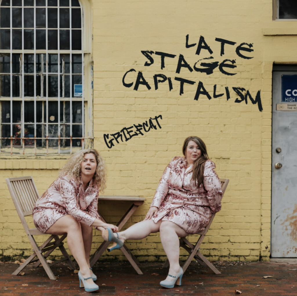 Griefcat sits in front of graffiti "Late Stage Capitalism" for its cover art